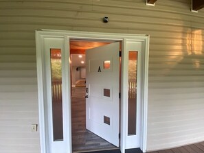 Une porte blanche portant le numéro « A », qui donne sur un escalier en bois.