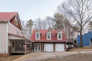 Une maison à deux étages avec un toit rouge, une véranda et deux portes de garage.