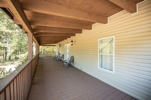 Un portico coperto con travi in legno, una ringhiera e vista sugli alberi.