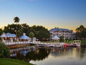Enjoy lakeside dining and relaxation at this serene lakeside hotel, featuring covered structures and a classic main building with a prominent roofline.