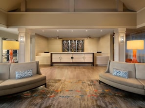 Welcome to our lobby, featuring a high ceiling, comfortable sofas, and a modern reception desk with a decorative partition.