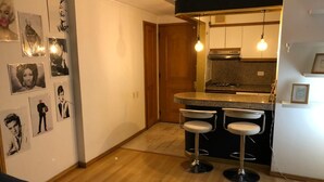 Une cuisine compacte avec un coin bar, un plancher en bois et des luminaires fixés au mur.
