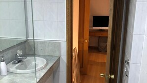 Une salle de bain moderne avec une douche à parois de verre, un lavabo doté d’un plan de toilette en marbre et des toilettes.