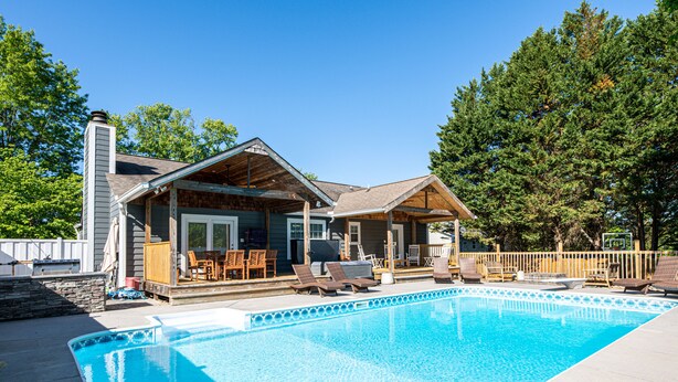Une maison avec une piscine, des chaises longues et un patio couvert.