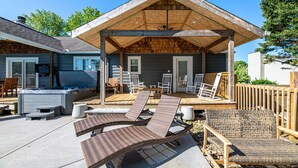 Un patio couvert aménagé avec du mobilier d’extérieur, notamment des chaises longues et une table, ainsi qu’un jacuzzi.