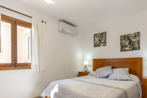 Bright and cozy bedroom featuring a double bed, air conditioning and warm neutral décor that creates a relaxing atmosphere.