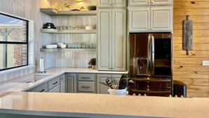 Une cuisine moderne avec des meubles de couleur gris clair, un réfrigérateur en acier inoxydable et un plafond en bois.