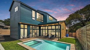 A modern two-story house with a swimming pool, large windows, and a covered patio area. - Pool, Hot Tub | Spacious Holiday Retreat for 14 (Austin)