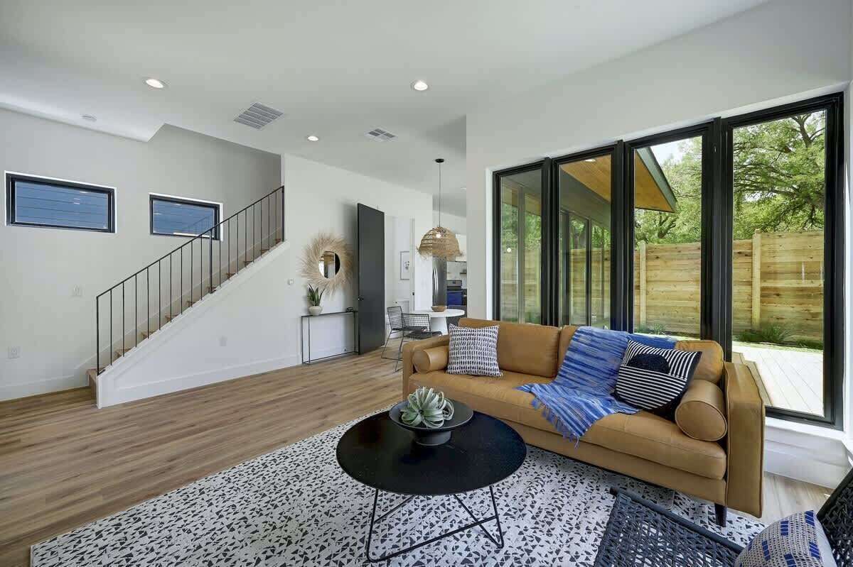 A modern living room with a sofa, coffee table, and large windows.