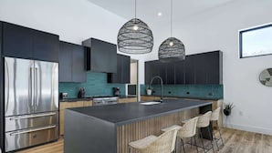 A modern kitchen with a large island, stainless steel appliances, and black pendant lighting. - Pool, Hot Tub | Spacious Holiday Retreat for 14 (Austin)