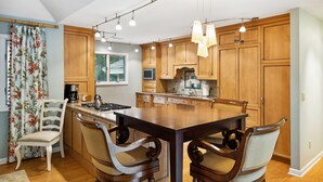 Een ruime keuken met houten kastjes, een groot eiland en moderne hanglampen.