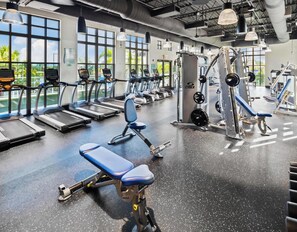 Une salle de sport équipée de tapis de course, d’appareils de musculation et de bancs.