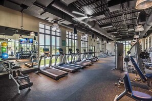 Une salle de sport équipée de tapis de course, de vélos d’exercice et d’appareils de musculation.