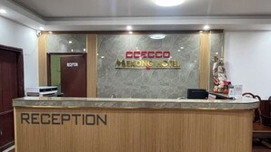 A reception desk at the Coecco Merong Hotel with a marble wall and a sign above it.