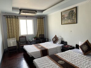 Habitación de hotel con dos camas, un escritorio, una silla y una ventana con cortinas.