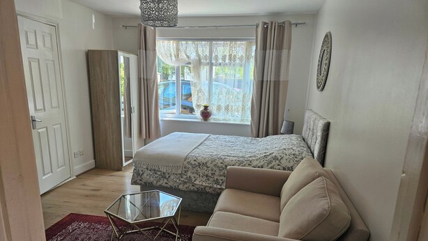A bedroom with a bed, a sofa, a glass coffee table, and a window with curtains. - Town Centre Studio - Sleeps 2 - Parking (Reading)