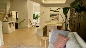 A modern living room with a sofa, a coffee table, and a large plant. There is a staircase leading to an upper level. - Contemporary 3BR Family-Friendly Oasis Close to the Lake (Toronto)
