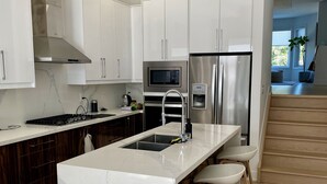 A modern kitchen with white cabinetry, a marble island, stainless steel appliances, and a wooden floor. - Contemporary 3BR Family-Friendly Oasis Close to the Lake (Toronto)