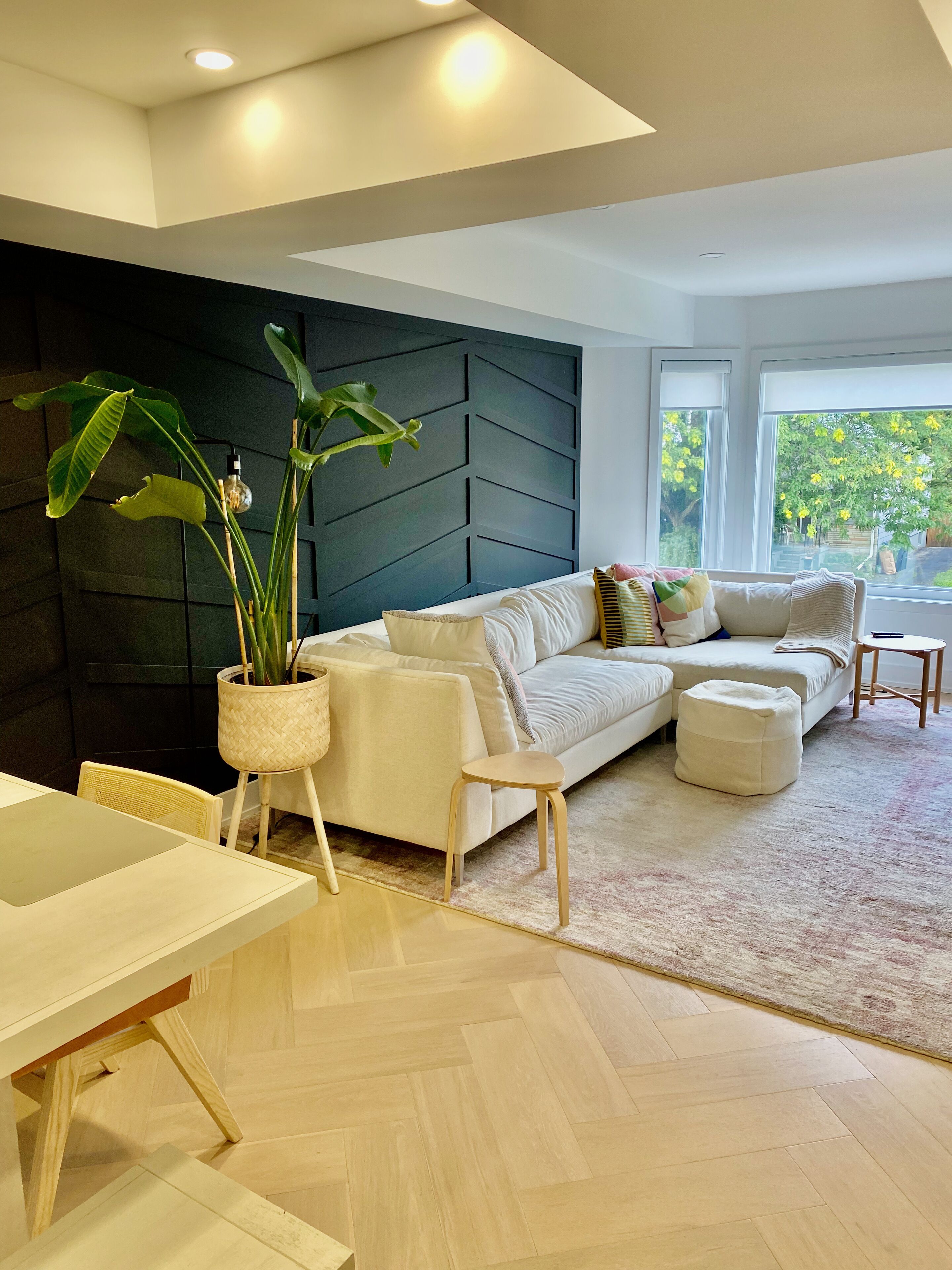 A modern living room with a sofa, ottoman, and a dining area with a table and chairs.