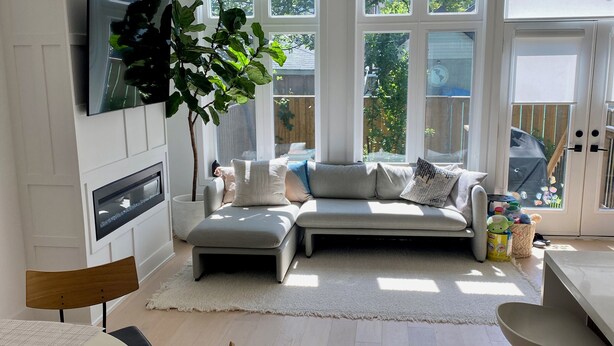 A modern kitchen with a built-in oven, a dining area with a round table, and a seating area with a sofa and a TV mounted on the wall. - Contemporary 3BR Family-Friendly Oasis Close to the Lake (Toronto)