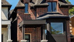 A modern two-story house with a brick facade, large windows, and a garage. - Contemporary 3BR Family-Friendly Oasis Close to the Lake (Toronto)