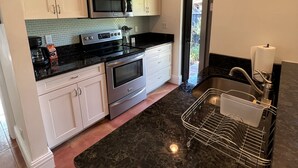 Een moderne keuken met witte kasten, roestvrijstalen apparatuur en een zwart granieten aanrecht.