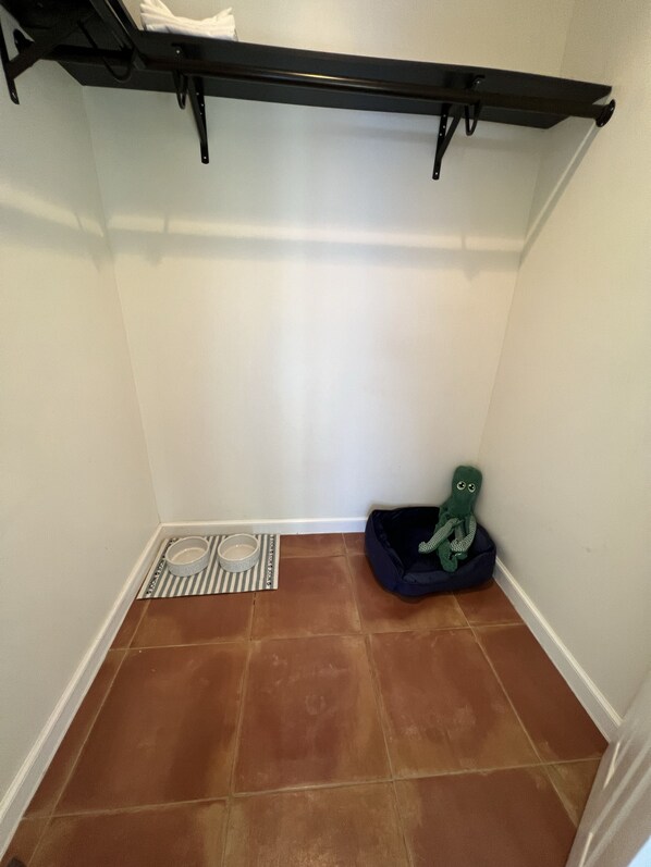 A small, tiled room with a black metal shelf, a striped mat, a white bowl, and a green plush toy. - ⭐️Beautiful Duplex in Victoria Park!⭐️ (Fort Lauderdale)