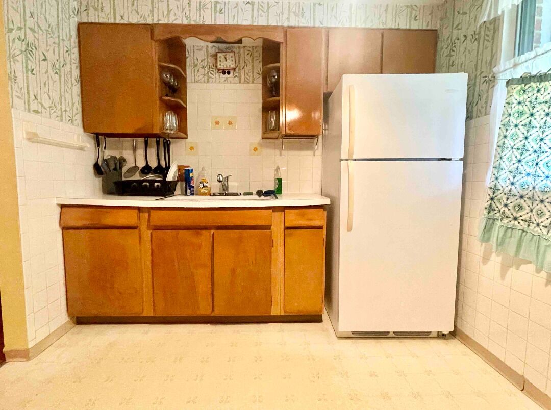 Una cucina con mobili in legno, un frigorifero bianco e uno schienale piastrellato.