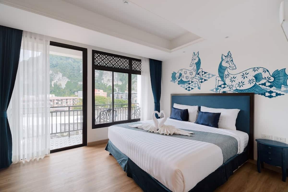 Un dormitorio con una cama grande, vista a un balcón y un mural de caballos en la pared.