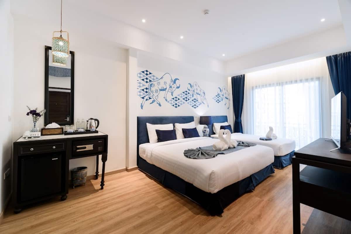 Una habitación de hotel con cama, mesitas de noche, escritorio y espejo.