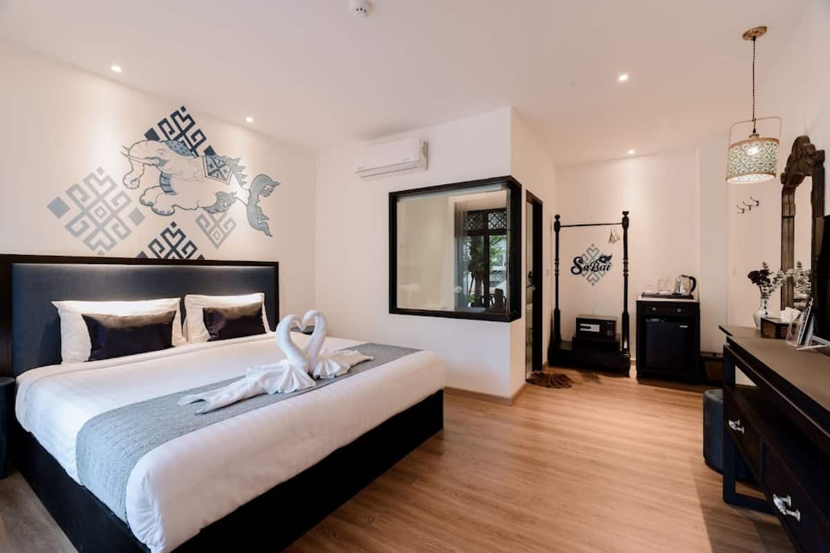 Una habitación de hotel moderna con una cama grande, un espejo, suelo de madera y una pared decorativa con un mural de un león.