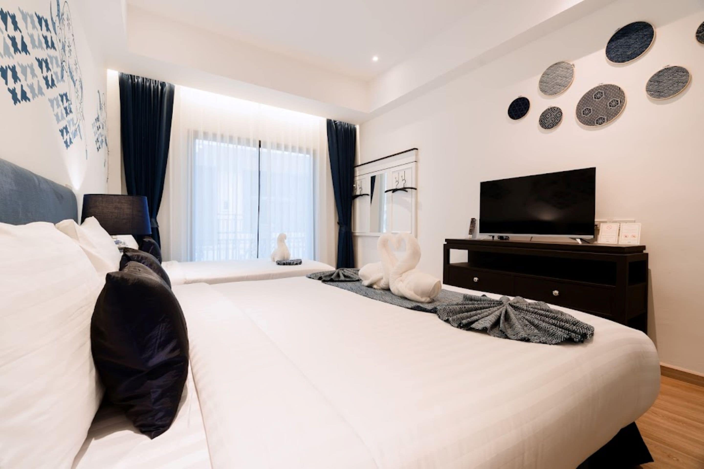 Una camera da letto moderna con un letto grande, una TV su una cassettiera e vista all'esterno da una finestra.