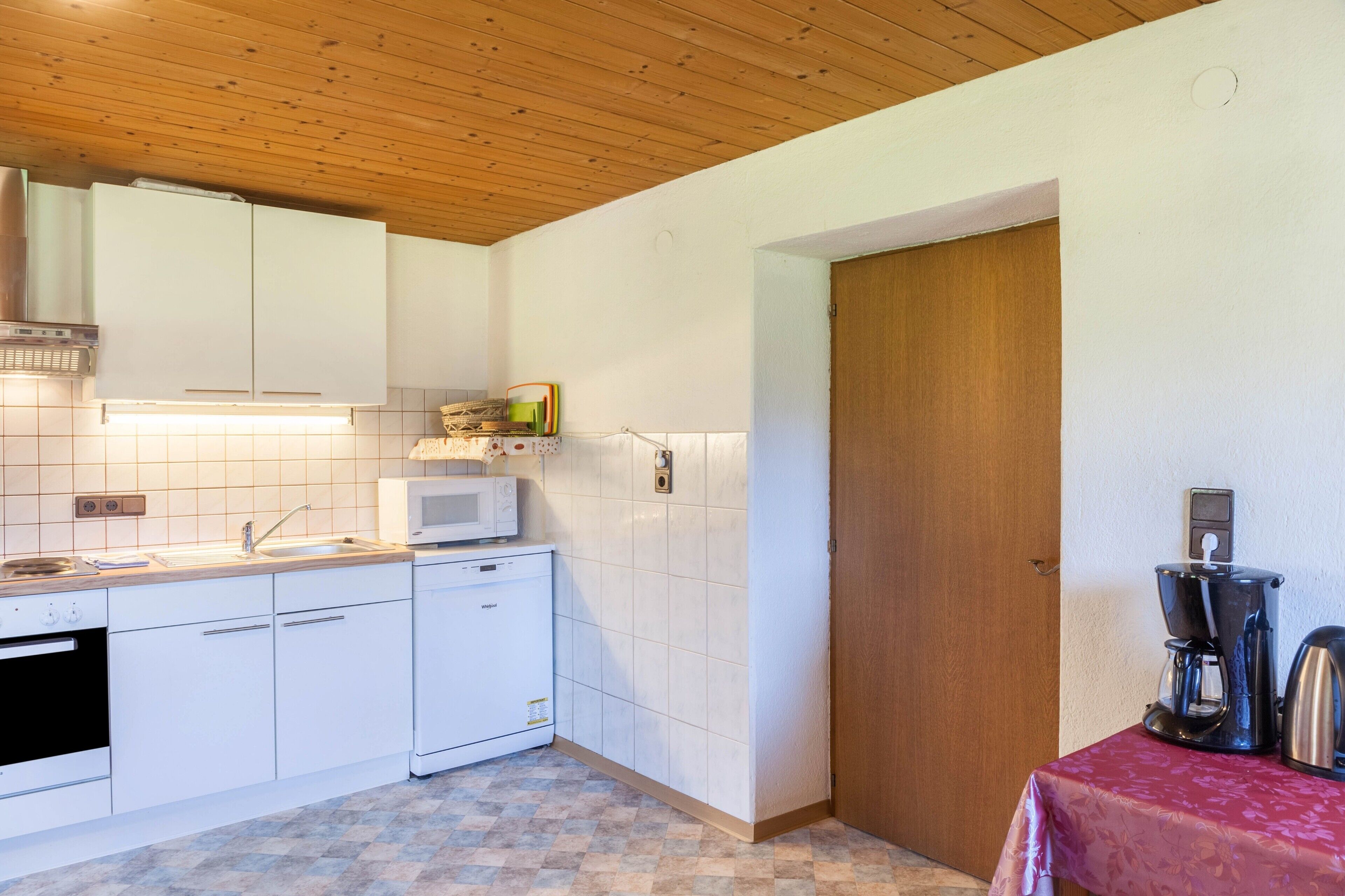 A kitchen with white cabinets, a microwave, a coffee maker, and a sink.