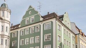 A multi-story building with a green facade, multiple windows, and a traditional architectural style. - Holiday Apartment Rathausplatz (Kempten)