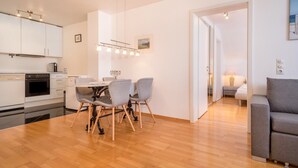 A modern kitchen with white cabinets, a dining table with chairs, and a sofa in a living area. - Holiday Apartment Rathausplatz (Kempten)
