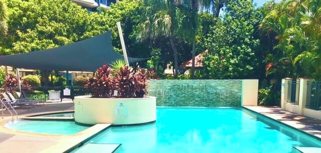 Ein Swimmingpool mit einem runden Blumenbeet und Liegestühlen.