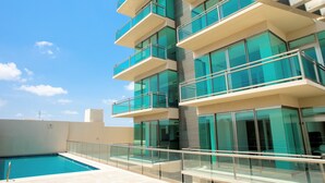 A modern building with multiple balconies and a swimming pool.