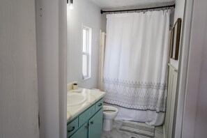 Bañera con ducha, toallas, jabón, papel higiénico
