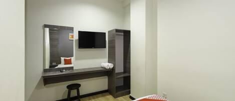 A modern hotel room with a bed, a desk with a chair, a flat-screen TV, a mirror, and a wardrobe.