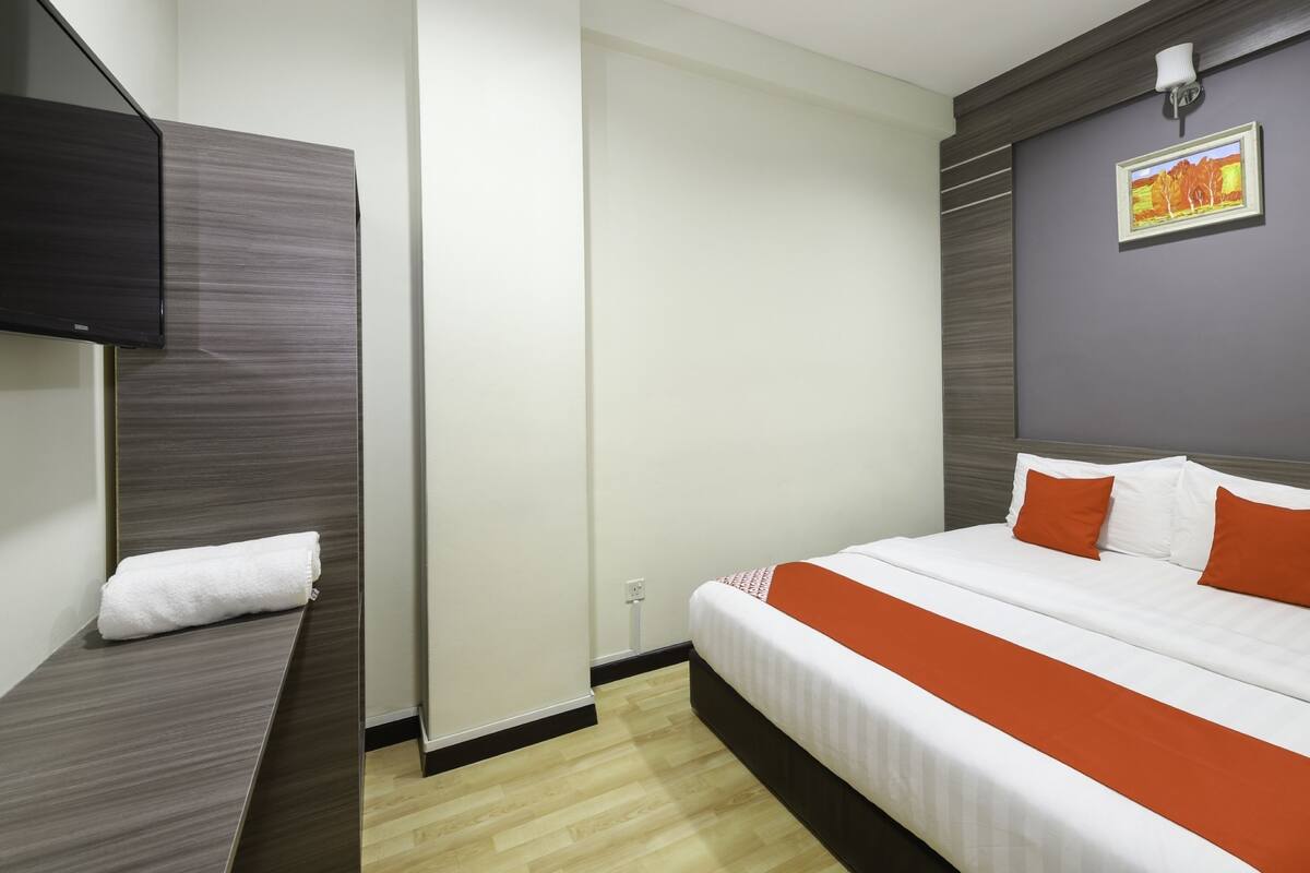 Une chambre d’hôtel moderne équipée d’un lit, d’un téléviseur à écran plat et d’un tableau au mur.