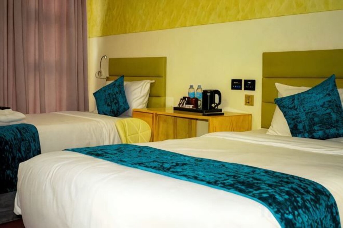 Een hotelkamer met twee bedden, een nachtkastje en een koffiezetapparaat.