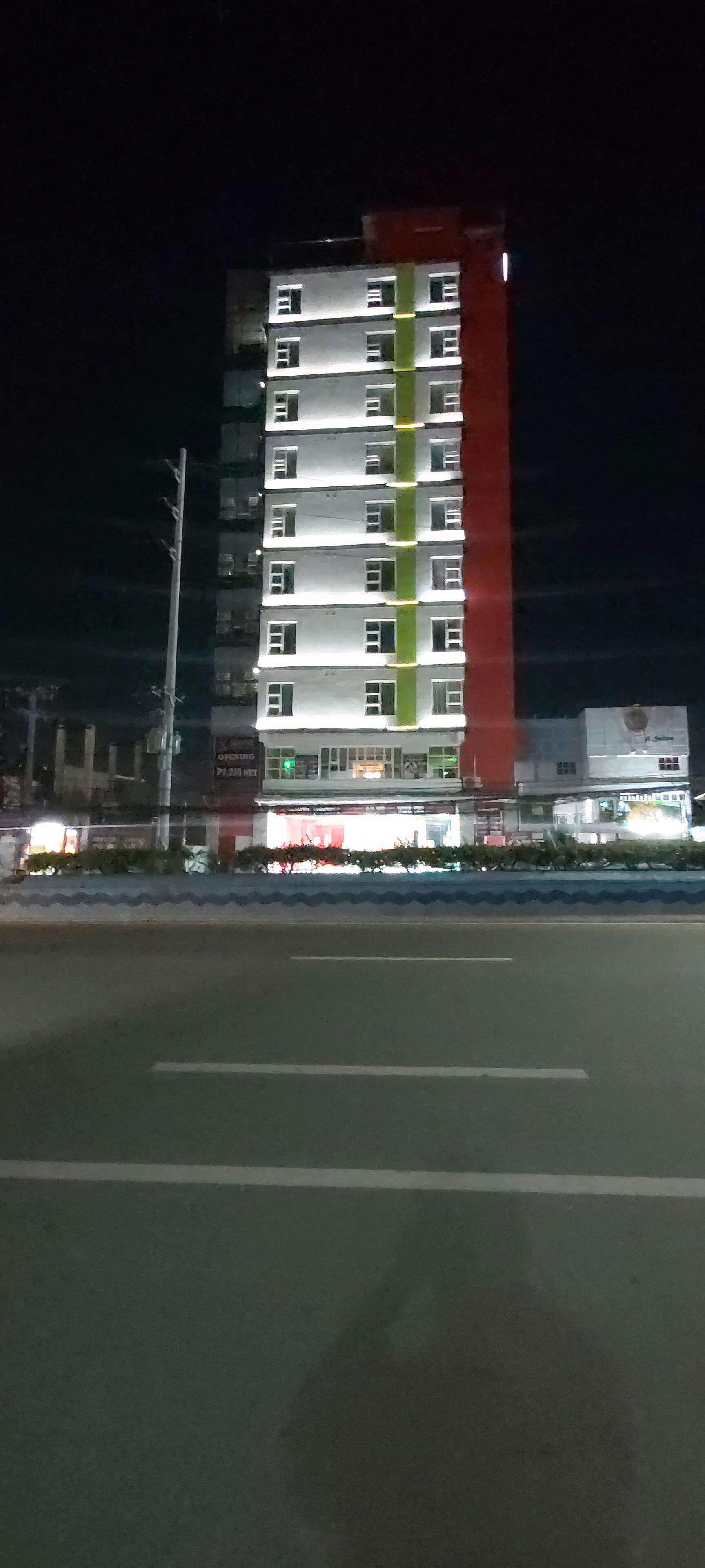 A multi-story building with a red vertical stripe, likely a hotel or apartment complex.