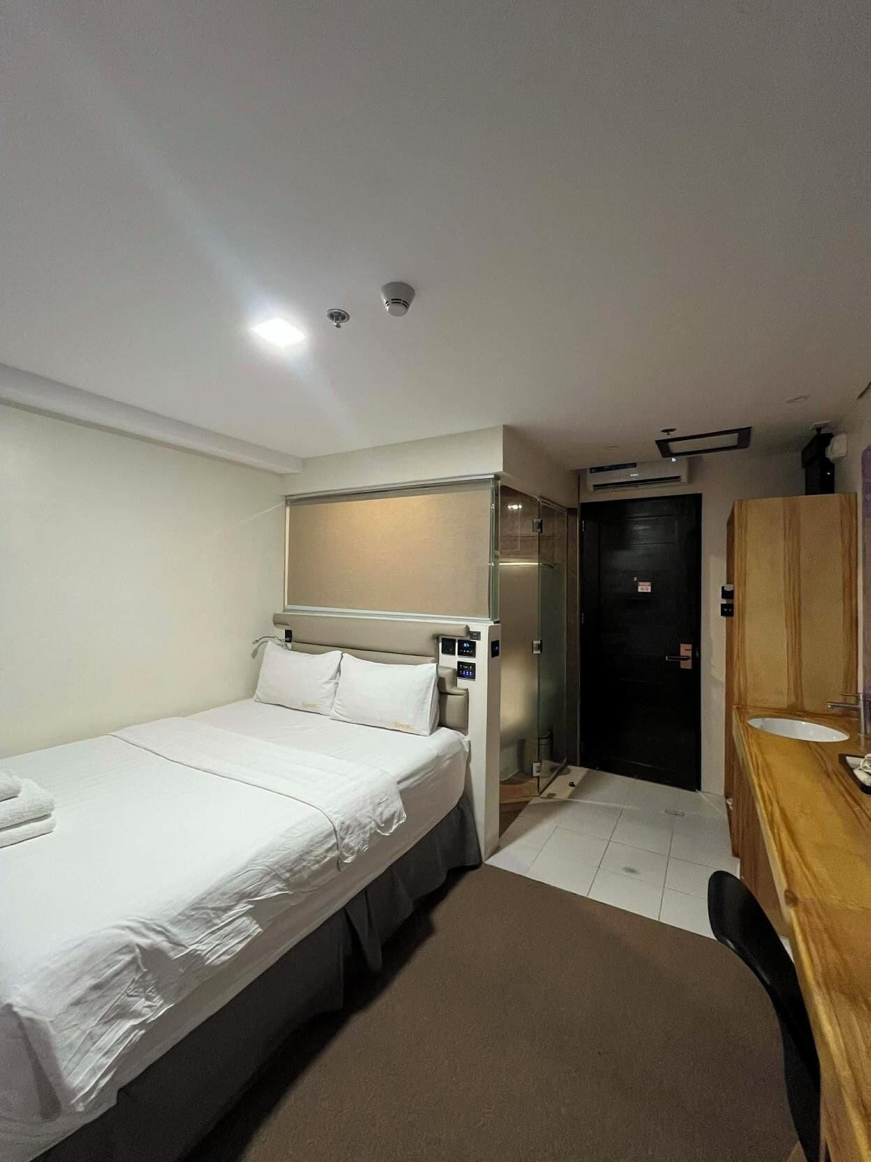 Una habitación de hotel con cama, mesita de noche y escritorio con silla.