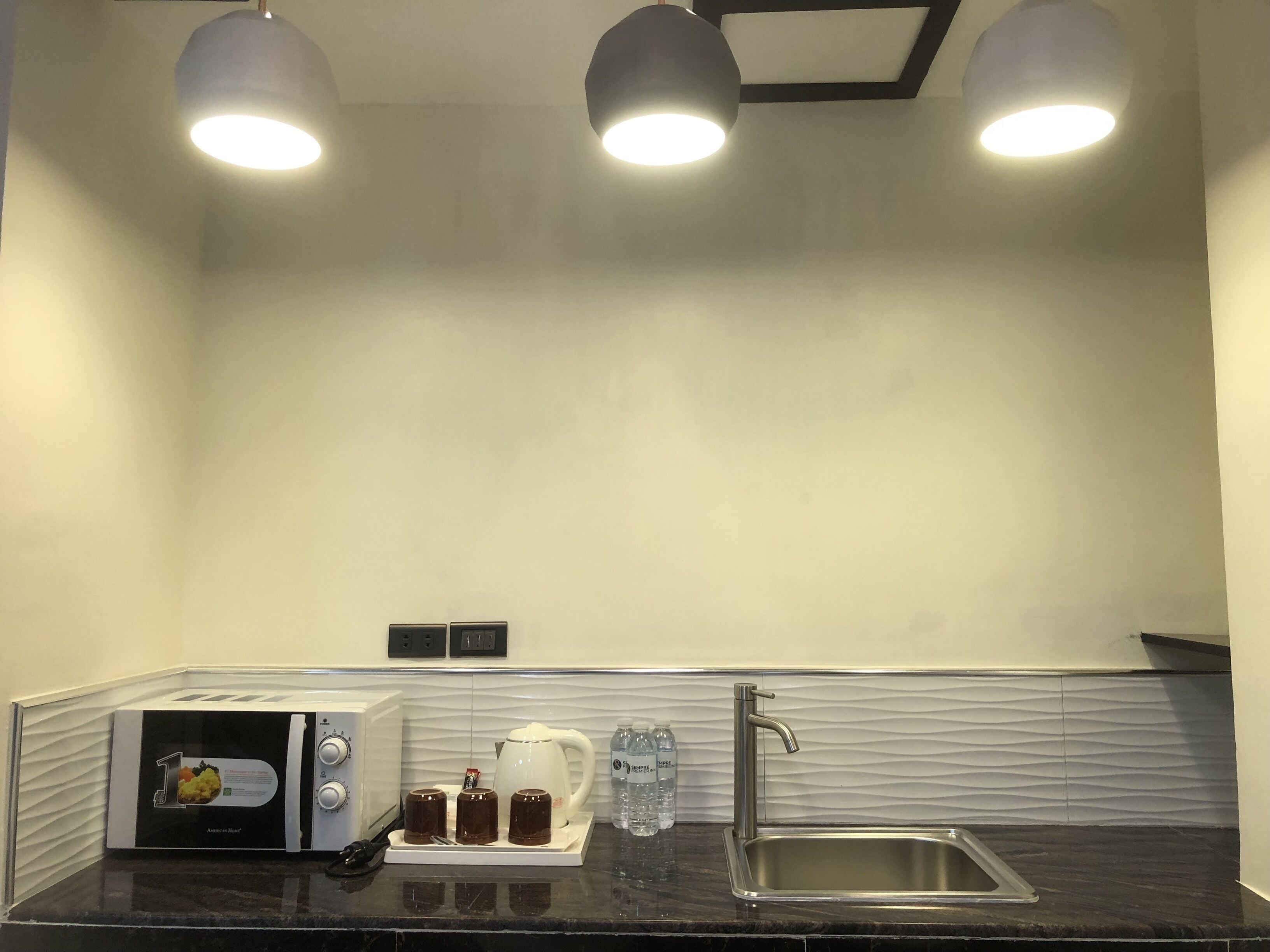 A modern kitchen with a black countertop, a stainless steel sink, a coffee maker, and a toaster.