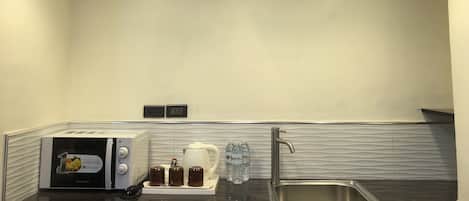 A modern kitchen with a black countertop, a stainless steel sink, a coffee maker, and a toaster.