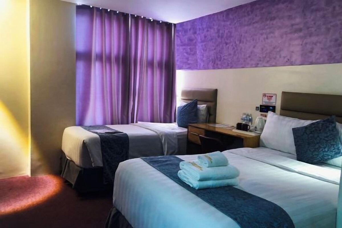 A hotel room with two beds, a desk, a chair, and a nightstand.
