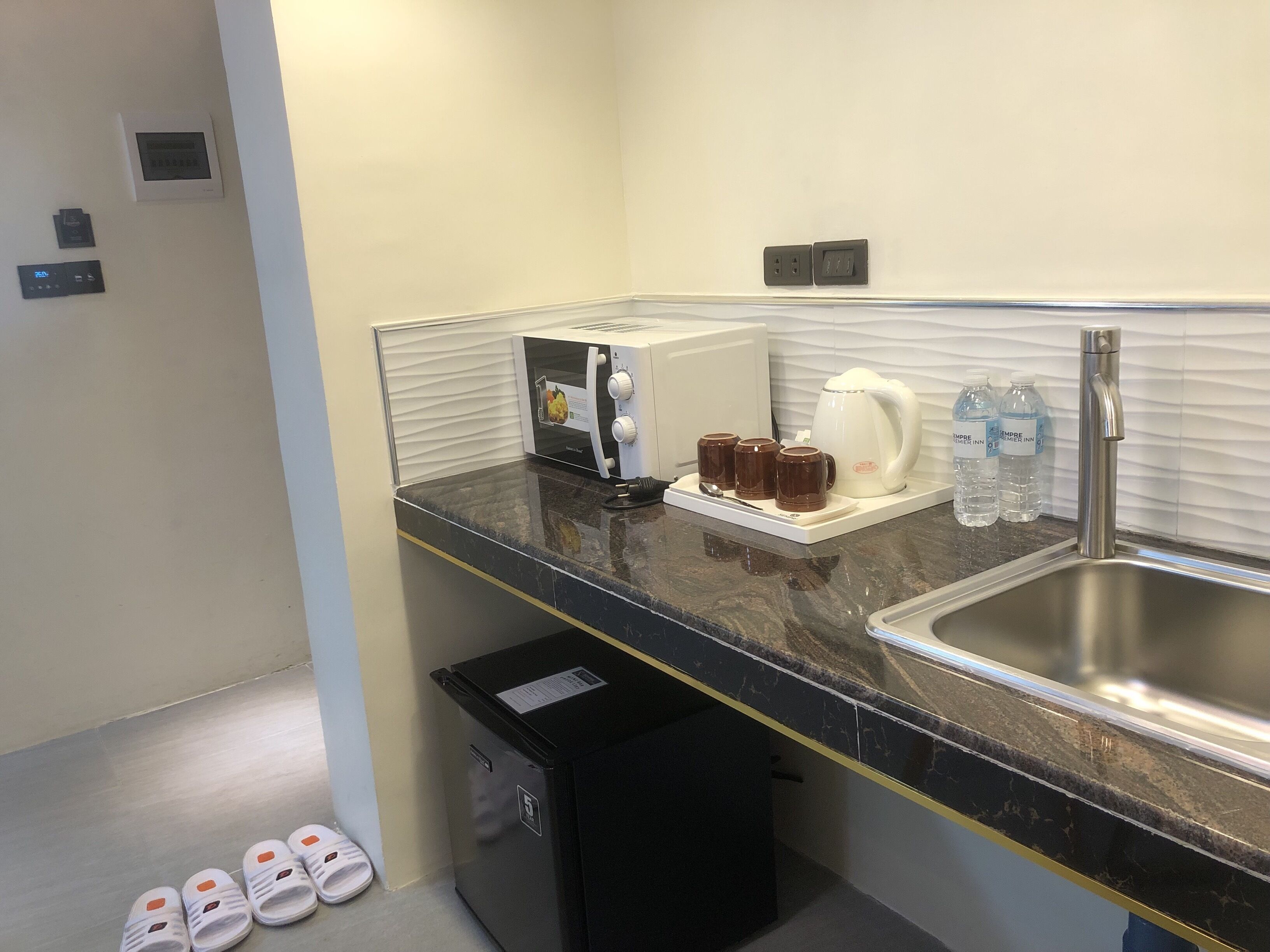 Un baño de hotel con lavamanos, cafetera y cubo de basura.