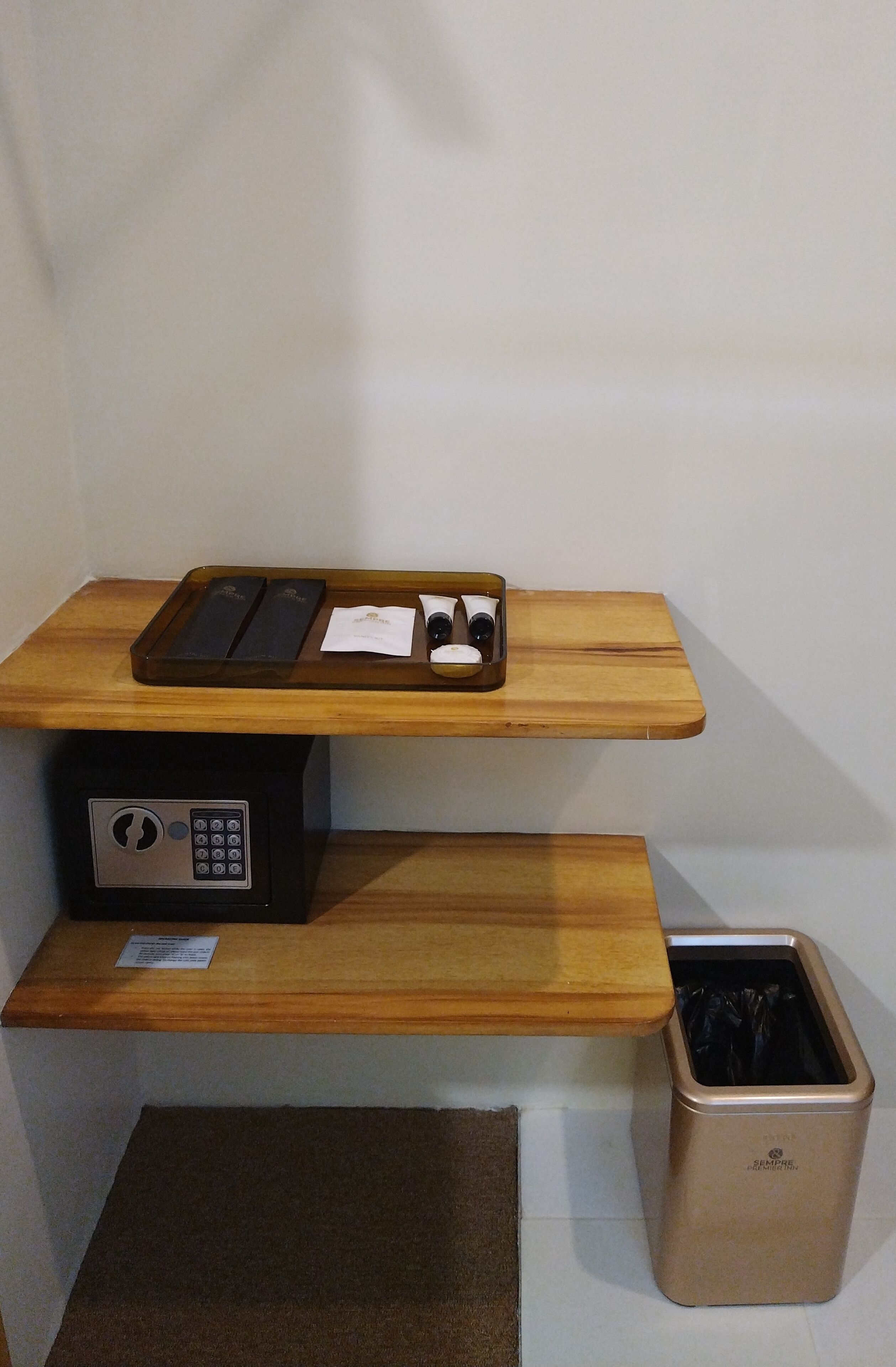 Un bureau en bois, un appareil électronique noir, un plateau contenant divers objets et une poubelle.