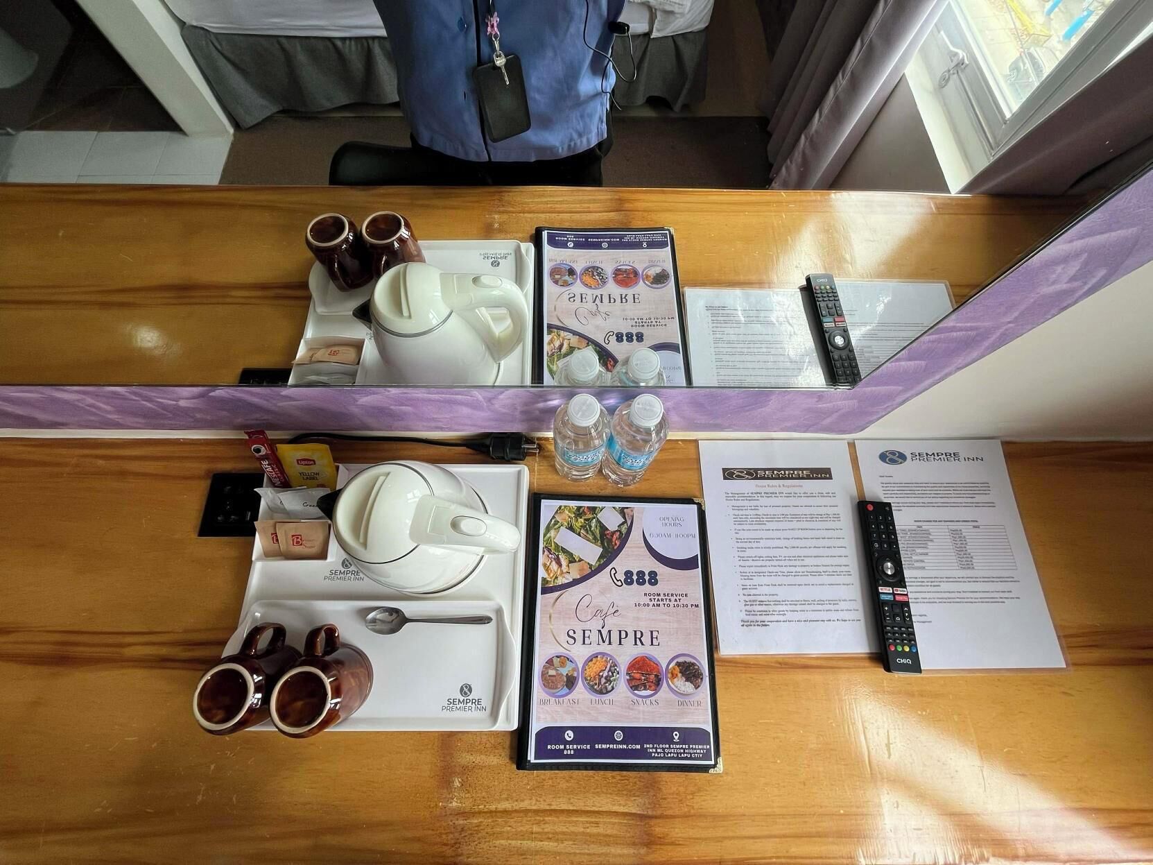 Un mostrador de recepción de hotel con una bandeja de servicio de café, un menú, un control remoto y un folleto.