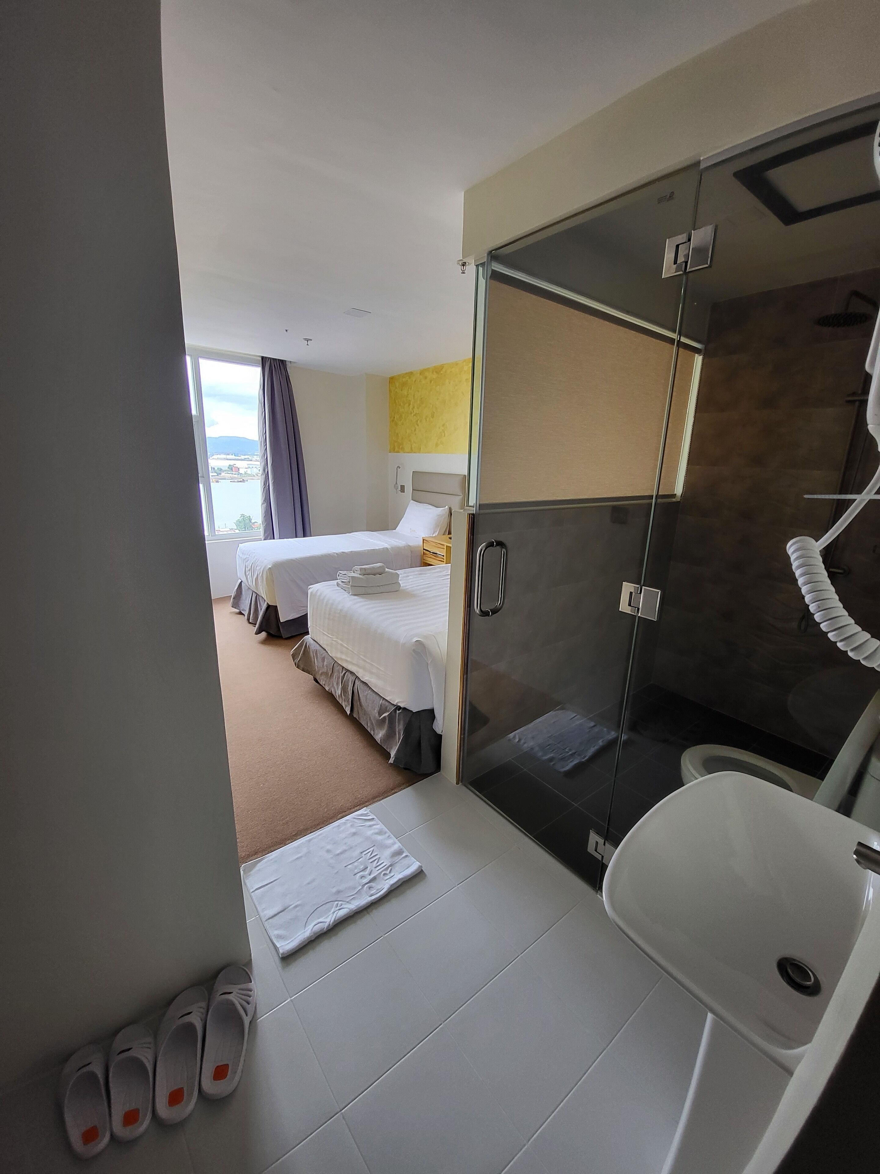 Habitación de hotel con dos camas, ducha y baño.